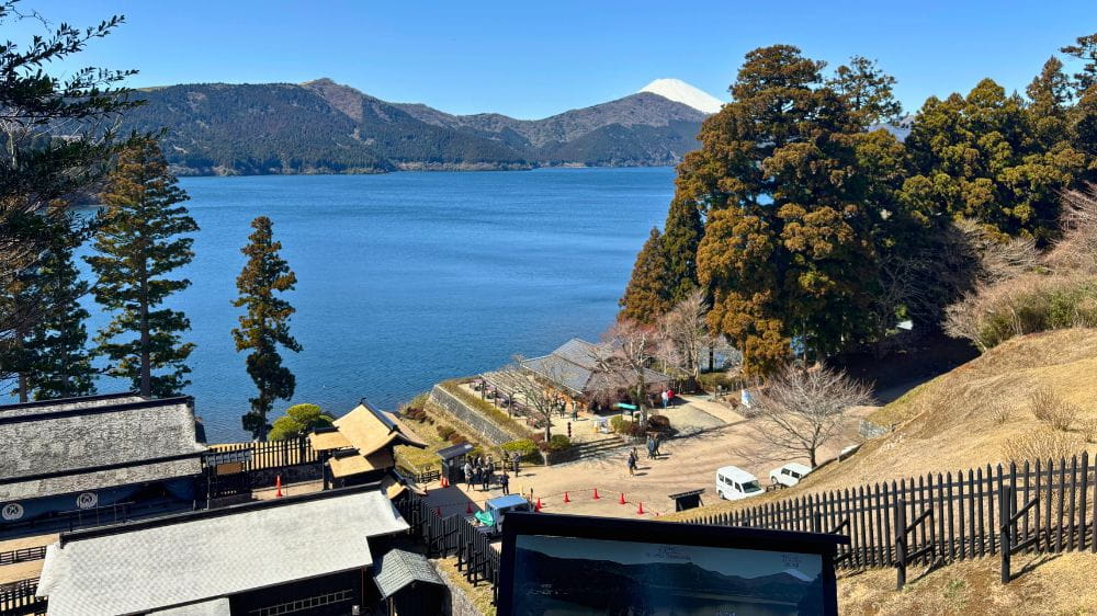 湖の奥に山が広がる。手前には黒い河原の建物が並び立つ。