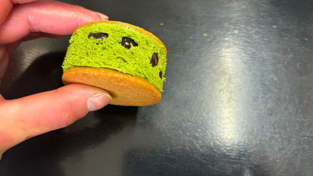 緑色のお菓子を手に持っている