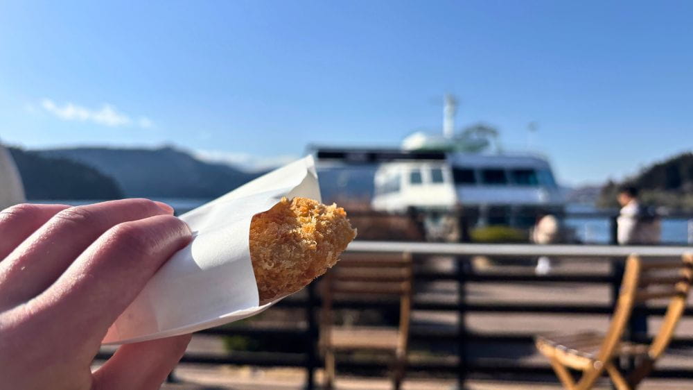 白い紙袋に包まれた茶色いコロッケ