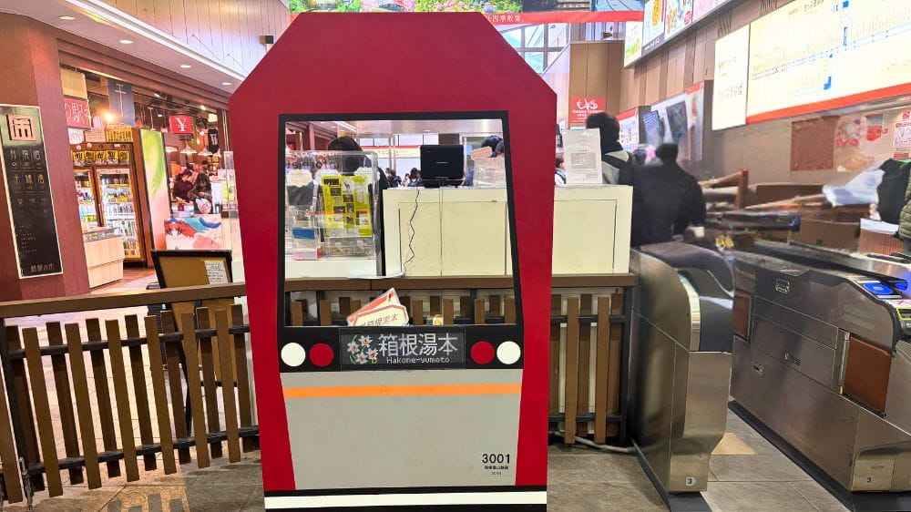 箱根湯本駅構内の改札前に設置された、赤い電車型の顔出しフォトパネル。中央の窓部分から人物が顔を出して記念撮影できる