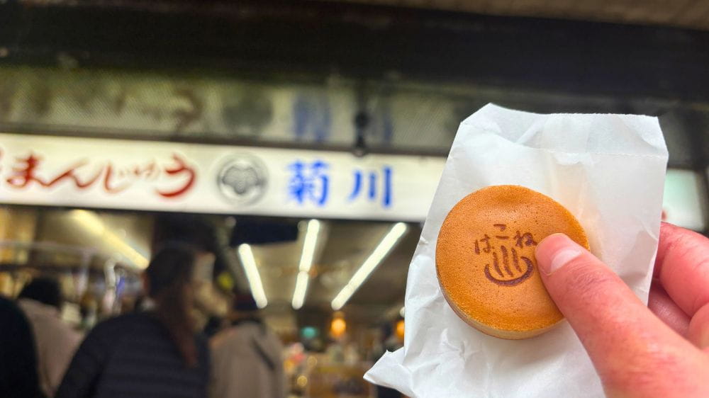 箱根湯本の食べ歩きで人気の温泉まんじゅうを店頭で手に持って撮影した写真。
