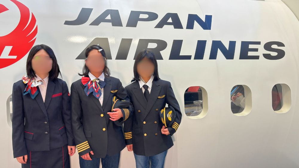 JALスカイミュージアムで制服を着用し、航空機の前で記念撮影する来場者の様子.

