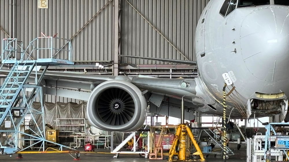 格納庫内で整備中の日本航空（JAL）航空機のエンジンと機体前方の様子。