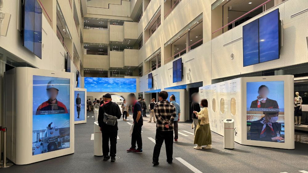 JALスカイミュージアムの館内展示スペースでパネルや映像を見学する来場者の様子。