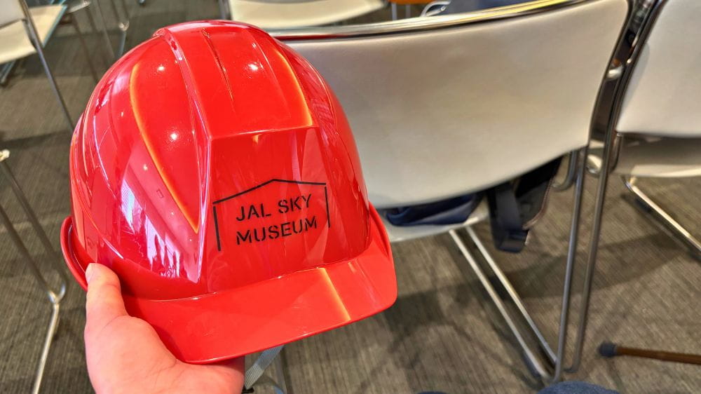 JALスカイミュージアムの見学で配布される赤いヘルメットを手に持つ様子。