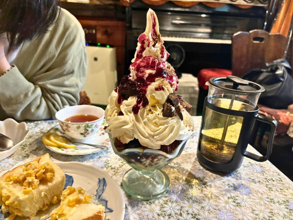 喫茶のんのんの珈琲ゼリーパフェ。たっぷりのホイップクリームとソフトクリーム、ベリーソースがのった人気スイーツ