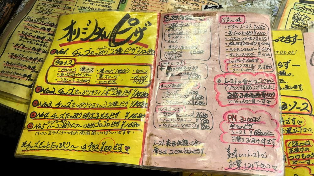 喫茶のんのんのオリジナルピザやチーズたっぷりトースト、マヨコーントーストなどが掲載された手書きメニュー表