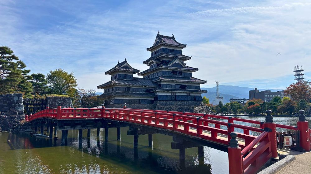 松本城公園の赤い埋橋と水堀、その奥にそびえる松本城天守の外観